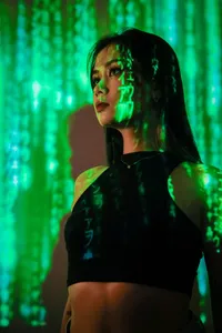A woman's face is illuminated by a projection of green, falling digital characters, symbolizing the vast amount of data AI processes.